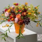 vaso arancione con fiori e bacche rosse
